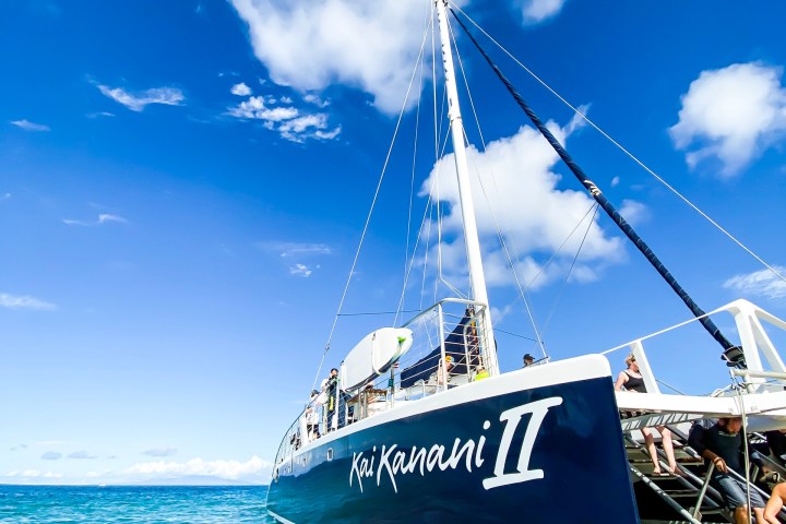 a blue and white boat sitting next to a body of water